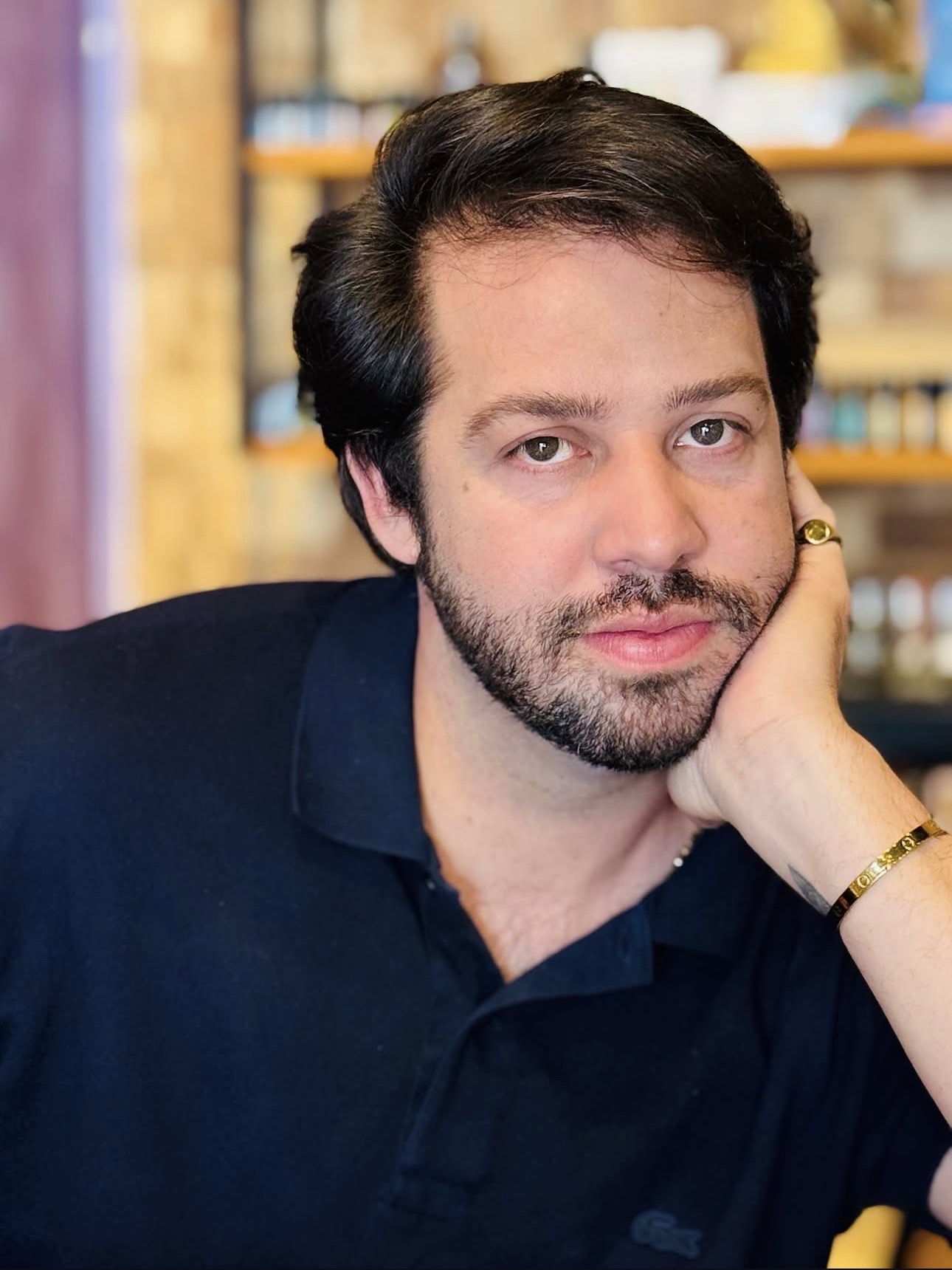 Retrato de Dieggo Santos em um café, apoiando o rosto na mão